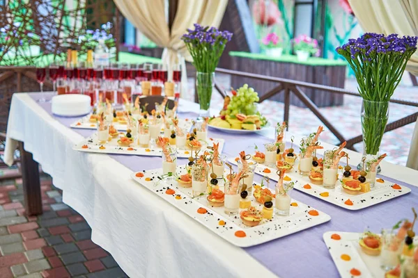 Buffet table with snacks, canape, appetizers and champagne, wine at luxury wedding reception, copy space. Serving food and drinks at event. Catering banquet table. Shrimp with sauce in glasses