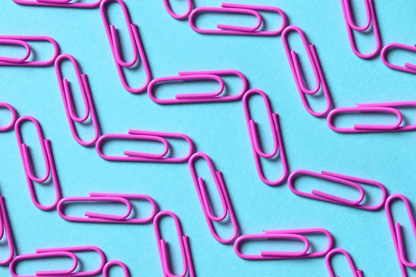 Purple (violet) paper clips on blue pastel background, copy space for text. Top view, flat lay. Back to school, college, education concept. Waves made from paperclips
