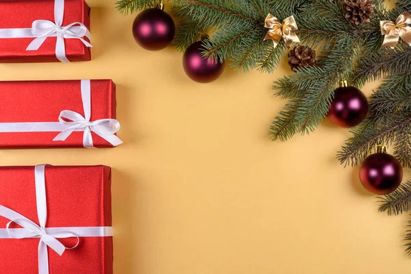 Noel arka plan kırmızı hediye kutuları, köknar ağacı dalları ile cam topları, çam kozalakları, tarçın ve Yıldız anason altın arka plan üzerinde boş alan. Kırmızı lüks yeni yıl hediye, kopya alanı