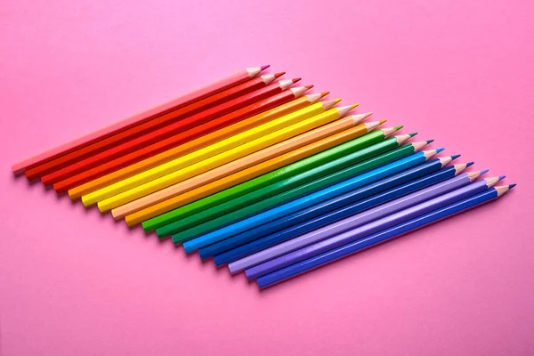 Colorful pencils of rainbow colors on pink pastel background, close up. Set of colorful pencils, copy space. Crayons. Top view, flat lay. Back to school, college concept. Abstract background