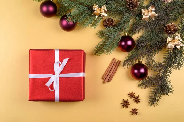 Noel arka plan kırmızı hediye kutusu, köknar ağacı dalları ile cam topları, çam kozalakları, tarçın ve Yıldız anason altın arka plan üzerinde boş alan. Kopya alanı düz yatıyordu, en iyi manzaralı 