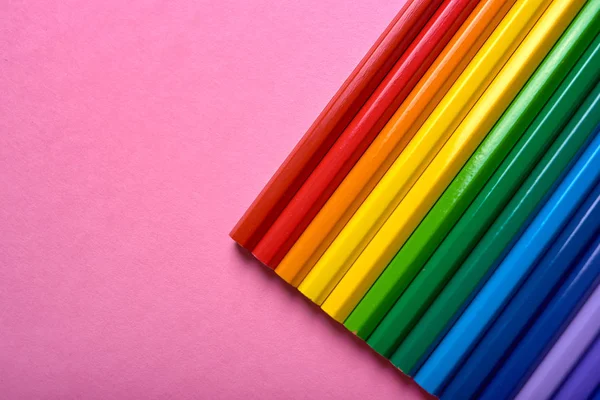 Colorful pencils of rainbow colors on pink pastel background, close up. Set of colorful pencils, copy space. Crayons. Top view, flat lay. Back to school, college concept. Abstract background