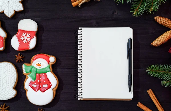 Noel arka plan beyaz boş kağıt defter, lezzetli ev yapımı gingerbread çerezleri, koyu ahşap masa, kopya alanı köknar ağacı dallarda ile. Üstten görünüm, düz yatıyordu