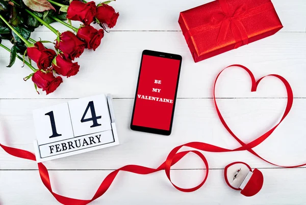 红玫瑰的花束 丝带形状如心 手机与标志是我的情人节 钻石戒指 礼品盒和2月14日木历 复制空间 贺卡模型 顶视图 平面布局 — 图库照片
