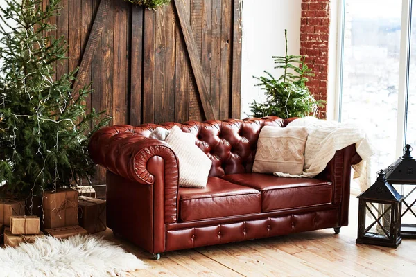 Ahşap kapı ve panoramik pencere, kopya alanı ile çatı odasında deri vintage kahverengi chesterfield kanepe Noel iç çam ağacı ve hediye kutuları