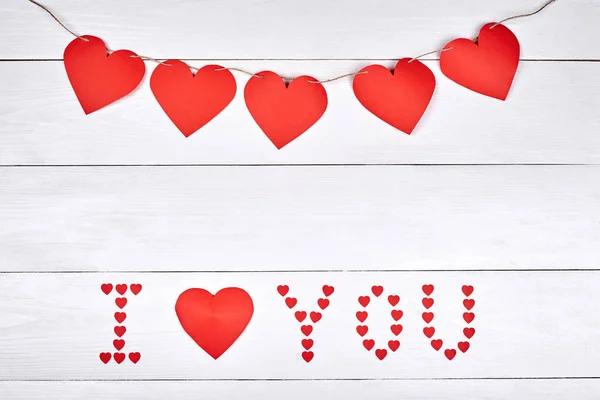 Valentines Day background with sign I Love You made from red paper hearts and garland, copy space. Greeting card mockup for Saint Valentine\'s Day. Symbol of love. Love concept, Top view, flat lay