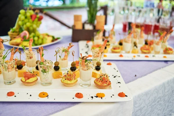 Buffet table with snacks, canape, appetizers and champagne, wine at luxury wedding reception, copy space. Serving food and drinks at event. Catering banquet table. Shrimp with sauce in glasses