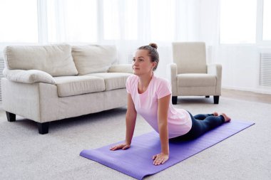 Pratik yoga adlı genç bir kadın portresi kapalı ev, uzay kopyalayın. Kobra poz, tam uzunlukta pratik kız. Rahatlatıcı ve yoga yapıyordum. Sağlık ve sağlıklı yaşam tarzı. Bhujangasana