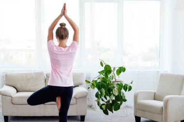 Denge yoga asana Vrikshasana pratik genç kadın portresi evde kapalı, kopya alanı, arkadan görünüm. Kız ağaç poz yapıyor. Rahatlatıcı ve yoga yapıyordum. Sağlık ve sağlıklı yaşam tarzı