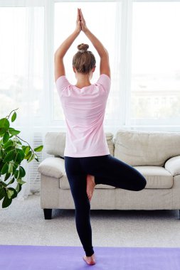 Denge yoga asana Vrikshasana pratik genç kadın portresi evde kapalı, kopya alanı, arkadan görünüm. Kız ağaç poz, tam uzunlukta yapıyor. Rahatlatıcı ve yoga yapıyordum. Sağlık ve sağlıklı yaşam tarzı