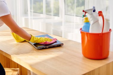 Toz pembe bez ile ahşap tablel dizüstü bilgisayarda temizlik sarı koruyucu lastik eldiven içinde kadın resim kırpılmış, uzay kopyalayın. Ev işleri, cleanig ve ev işleri kavramı