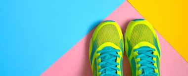 Çift spor ayakkabı renkli arka plan üzerinde. Pembe, mavi ve sarı pastel arka plan, kopya alanı üzerinde yeni spor ayakkabıları. Genel gider atış koşu ayakkabıları. Üstten görünüm, düz yatıyordu