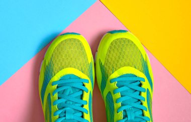 Çift spor ayakkabı renkli arka plan üzerinde. Pembe, mavi ve sarı pastel arka plan, kopya alanı üzerinde yeni spor ayakkabıları. Genel gider atış koşu ayakkabıları. Üstten görünüm, düz yatıyordu