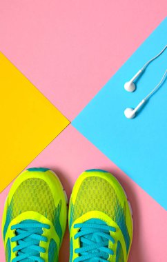 Spor ayakkabı çalışan görünümü üst ve beyaz kulaklık pembe, mavi ve sarı pastel arka plan üzerinde atlama, metin için yer kopyalayın. Düz yatıyordu. Spor, fitness kavramı, sağlıklı yaşam tarzı
