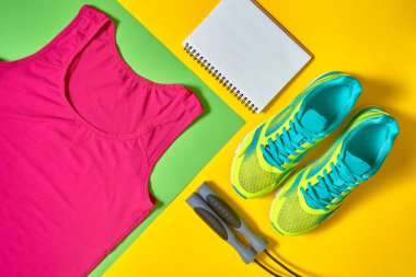 Spor ayakkabı, kadın üst sutyen, beyaz boş defter ve renkli sarı ve yeşil isimlerinözgeçmişlerini üzerinde ip atlama alanı kopyalayın. Üstten görünüm, düz yatıyordu. Spor ve sağlıklı yaşam konsepti, düz yatıyordu