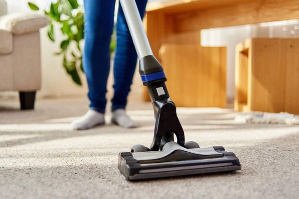Oturma odasında, kopya alanı elektrikli süpürge ile halı yıkama Jeans genç kadının kapatın. Ev işleri, ev, bahar-cleanig ve ev işleri kavramı. Ev temizliği 