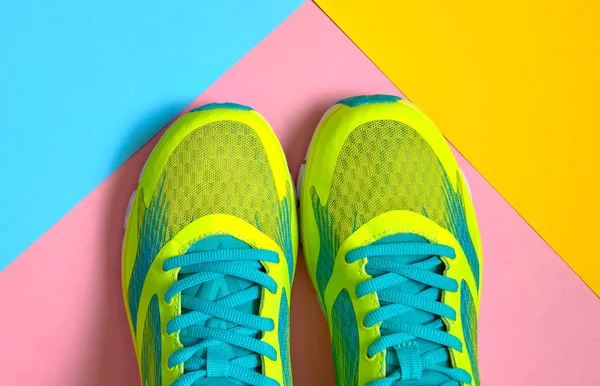 Pair of sport shoes on colorful background. New sneakers on pink, blue and yellow pastel background, copy space. Overhead shot of running shoes. Top view, flat lay