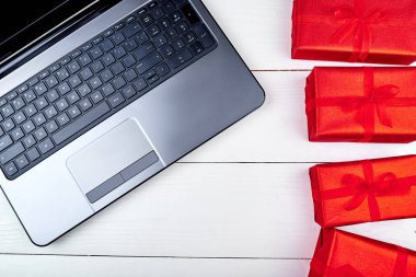 Açık dizüstü bilgisayar ve kırmızı hediye kutuları beyaz ahşap masa ofis, kopya alanı. Düz yatıyordu, en iyi görünüm. Online alışveriş, tatil satış. Sevgililer günü, 8 Mart Kadınlar günü, anneler günü