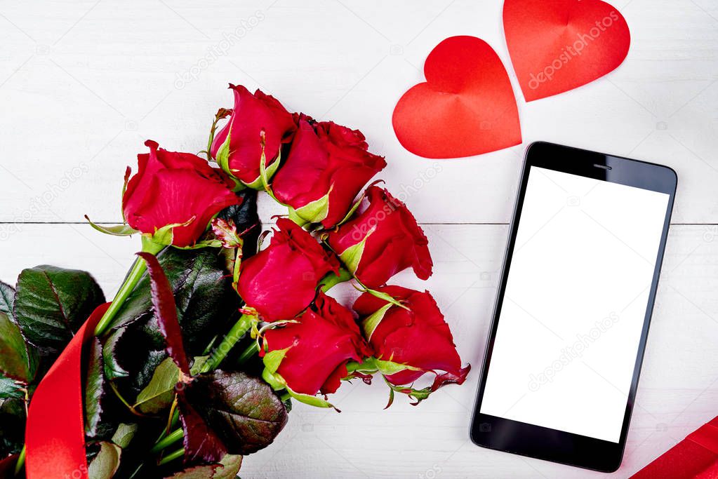 Bouquet of red roses, paper hearts and cellphone with empty blank screen on white background, copy space. Valentines day, Womens Day, Mothers Day. Top view, flat lay