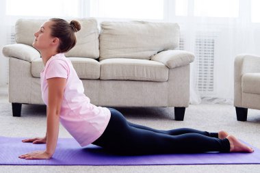 Pratik yoga adlı genç bir kadın portresi kapalı ev, uzay kopyalayın. Kobra poz, tam uzunlukta pratik kız. Rahatlatıcı ve yoga yapıyordum. Sağlık ve sağlıklı yaşam tarzı. Bhujangasana