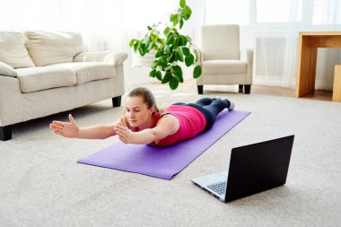 Dizüstü bilgisayarda, kopya alanı Eğitim Online egzersiz için sırt üstü yere vasıl ev, yapmak güzel ve genç birbayan. Tam uzunlukta portre. Çalışma dışarı egzersiz yoga, pilates,