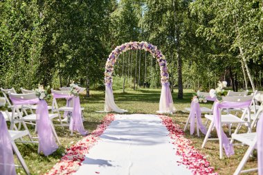 Düğün töreni için yer. Düğün kemer kopya alanı bez ve çiçek ve açık havada, kemerli her tarafında sandalye ile dekore edilmiştir. Yeşil çimenlerin üzerinde Konuklar için boş ahşap sandalyeler. Düğün Kur
