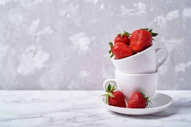 Olgun organik çilek kopya alanı gri mermer zemin üzerine beyaz seramik kase. Sağlıklı gıda kavramı, natürmort