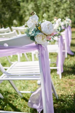 Beyaz ahşap sandalye mor bez ve beyaz şakayık çiçekleri açık havada, kemerli her tarafında yer kopyalayın. Düğün töreni için hazırlanan Konuklar için boş sandalyeler