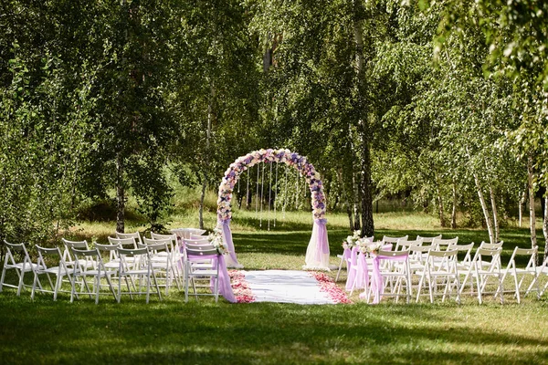 結婚式のための場所 結婚式のアーチはコピー スペース花と屋外で アーチの両側に椅子の布で飾られました 緑の草原の空の木の椅子 結婚式のセットアップ — ストック写真