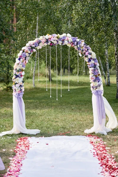 Place for wedding ceremony. Wedding arch decorated with cloth and flowers and chairs on each side of archway outdoors, copy space. Wedding setup