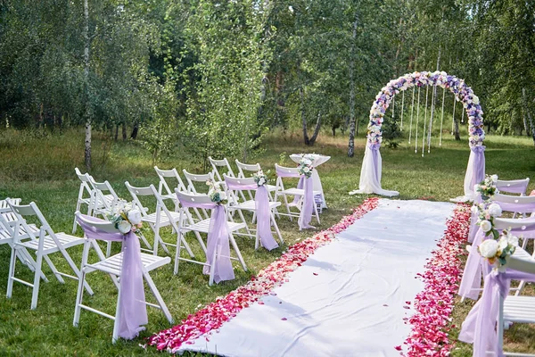 結婚式のための場所 結婚式のアーチはコピー スペース花と屋外で アーチの両側に椅子の布で飾られました 緑の草原の空の木の椅子 結婚式のセットアップ — ストック写真