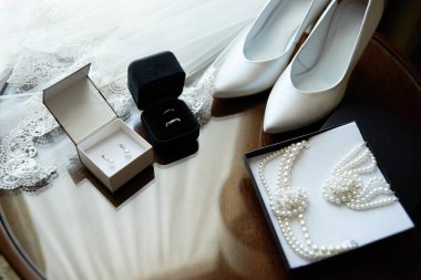 Lüks Beyaz Bayan ayakkabı, peçe, Gümüş Alyanslar ve ahşap masa, kopya alanı üzerinde gelin takı (inci kolye, bileklik ve küpe). Düğün sabah. Gelin aksesuarları. Evlilik kavramı