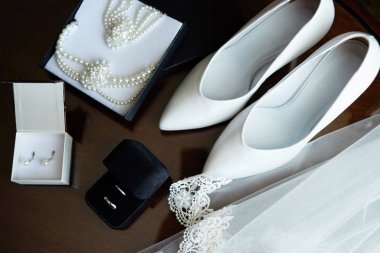 Gelin aksesuarları. Lüks Beyaz Bayan ayakkabı, peçe, Gümüş Alyanslar ve ahşap masa, kopya alanı üzerinde gelin takı (inci kolye, bileklik ve küpe). Evlilik kavramı. Üstten görünüm