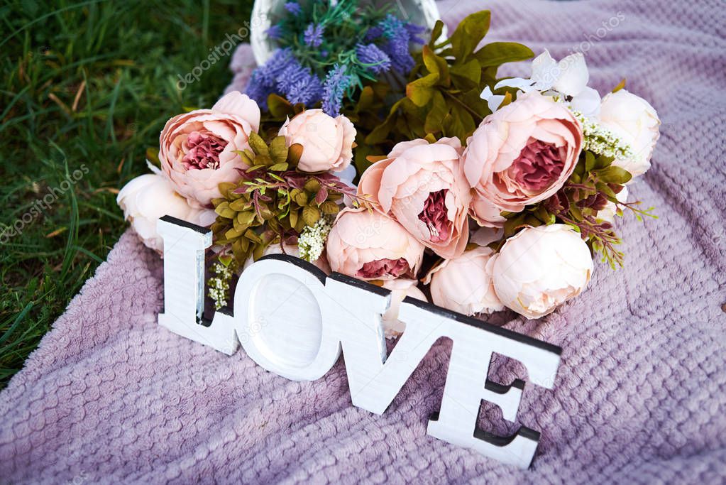 Word love and bouquet of pink peony flowers on purple background outdoors, copy space. Wedding decorations. Valentines day, love concept