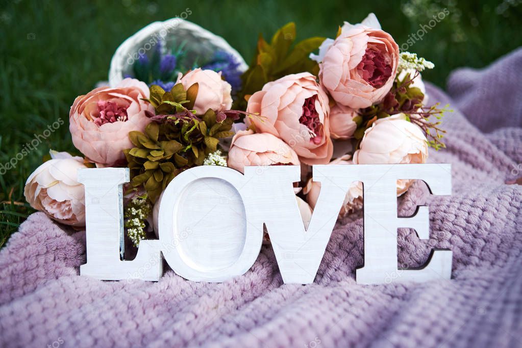 Word love and bouquet of pink peony flowers on purple background outdoors, copy space. Wedding decorations. Valentines day, love concept