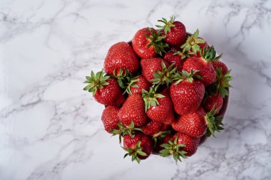 Organik olgun çilek kopya alanı gri mermer zemin üzerine beyaz seramik kase. Sağlıklı gıda kavramı, Natürmort. Üstten Görünüm, düz yatıyordu