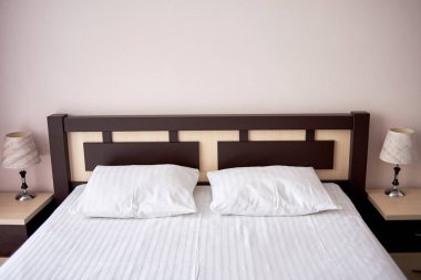 İki beyaz yumuşak yastık yatak otel yatak odası iç, kopya alanı ahşap karyola ile. Başucundaki klasik lamba