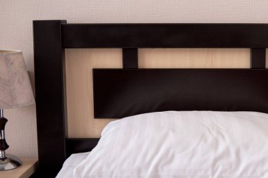 Beyaz yumuşak yastık kahverengi ahşap yatak başı otel yatak odası iç, kopya alanı ile tek kişilik yatak üzerinde kapat