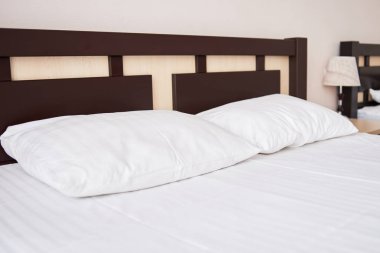 İki beyaz yumuşak yastık yatak otel yatak odası iç, kopya alanı ahşap karyola ile. Başucundaki klasik lamba