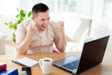 Heyecanlı genç adam yumruklarını kaldırarak zafer kazanıyor. Mutlu adam görevini tamamladı ve görevdeki başarısını kutladı. Ben bir kazananım! Ah evet! Yaptım! Yapılan işten memnun.