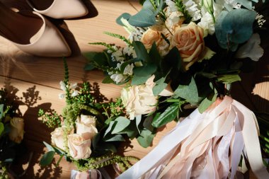 Gelin buketi pembe Gül ve yeşil saten kurdeleler, yaka çiçeği ve ahşap arka plan, kopya alanı üzerinde bej gelinin ayakkabı ile. Düğün kavramı. Üstten Görünüm, düz yatıyordu 