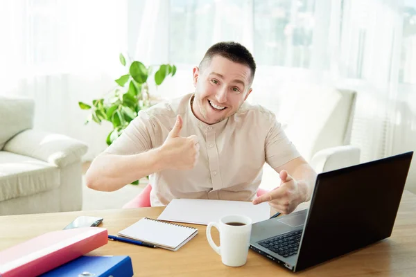 Satisfied businessman with work done in office. Happy young man working on laptop while sitting at workingplace