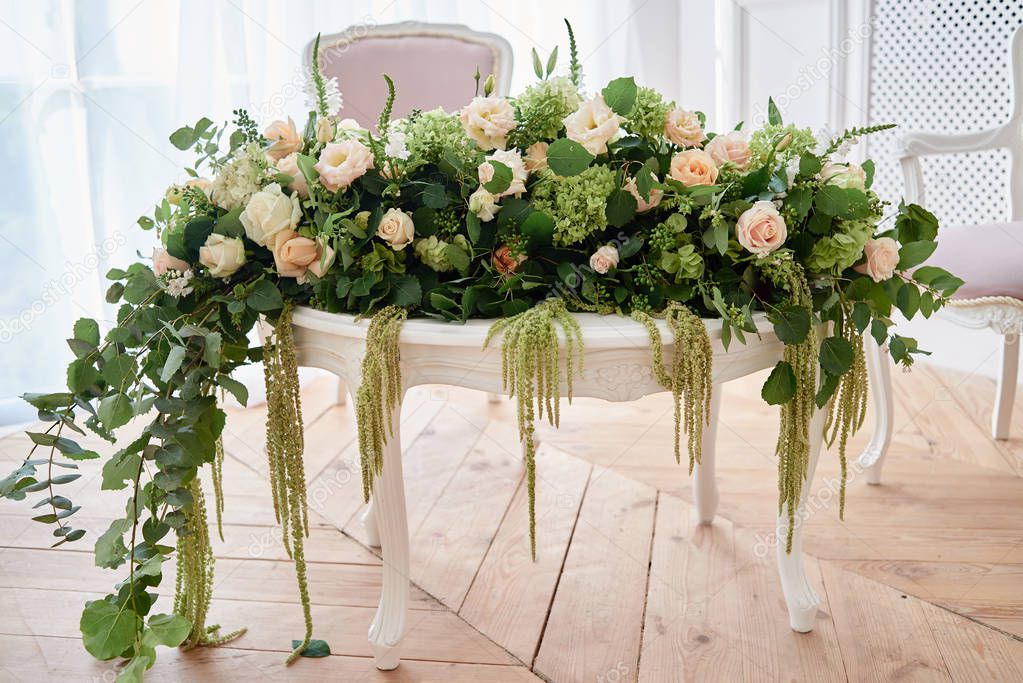 Luxury floral arrangement of pink and beige roses, freesia, hydrangea and amaranth on white wood table, copy space.  Flowers composition for wedding presidium, beautiful decorations