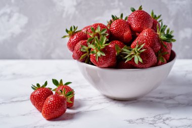 Gri alçı duvar arka plan üzerinde beyaz seramik kase organik olgun çilek, kopya alanı. Sağlıklı gıda kavramı, natürmort