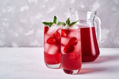 Taze çilek limonata buz ve nane bardak ve beyaz masa arka plan üzerinde sürahi, kopya alanı ile. Soğuk yaz içkisi. Berry kokteyl ile Köpüklü cam