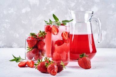 Taze çilek limonata buz ve nane bardak ve beyaz masa arka plan üzerinde sürahi, kopya alanı ile. Soğuk yaz içkisi. Berry kokteyl ile Köpüklü cam