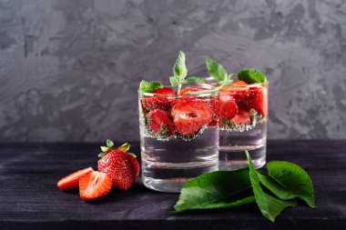 Detoks ahşap masa arka plan üzerinde köpüklü bardak çilek ve nane ile su aşılanmış, kopya alanı. Soğuk yaz içkisi. Maden suyu