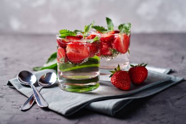 Detoks koyu masa arka plan üzerinde köpüklü gözlük çilek ve nane ile su aşılanmış, kopya alanı. Soğuk yaz içkisi. Maden suyu