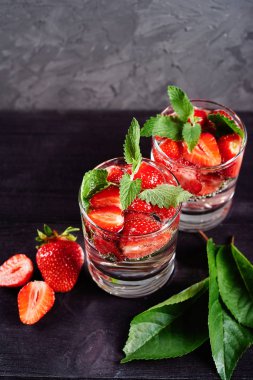 Detoks ahşap masa arka plan üzerinde köpüklü bardak çilek ve nane ile su aşılanmış, kopya alanı. Soğuk yaz içkisi. Maden suyu