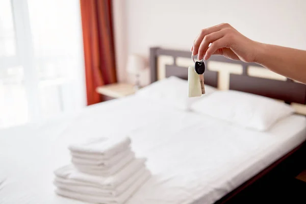 Mujer sosteniendo en la mano la llave de la habitación con etiqueta en blanco en la suite del hotel , — Foto de Stock